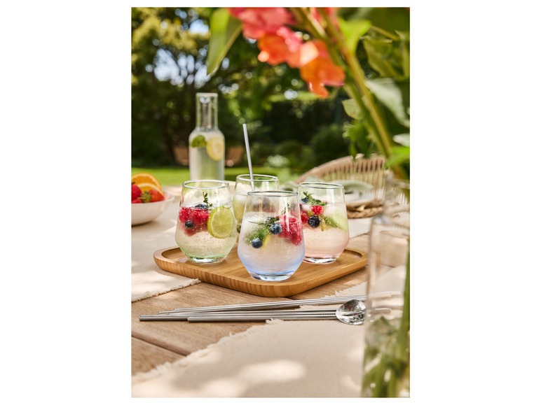 Des verres avec des fruits et des glaçons sur un plateau en bois.