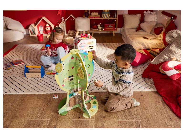 Deux enfants jouent avec un centre d'activités en bois et un ensemble d'outils jouets dans une pièce douillette.