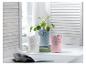 Trois pots en métal avec un motif élégant, deux avec des plantes et un sur une pile de livres