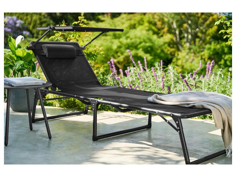 Transat de jardin noir avec coussin et pare-soleil, à côté d'une petite table avec des livres.