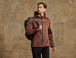 Un homme portant une veste softshell marron à capuche et un sac à dos.