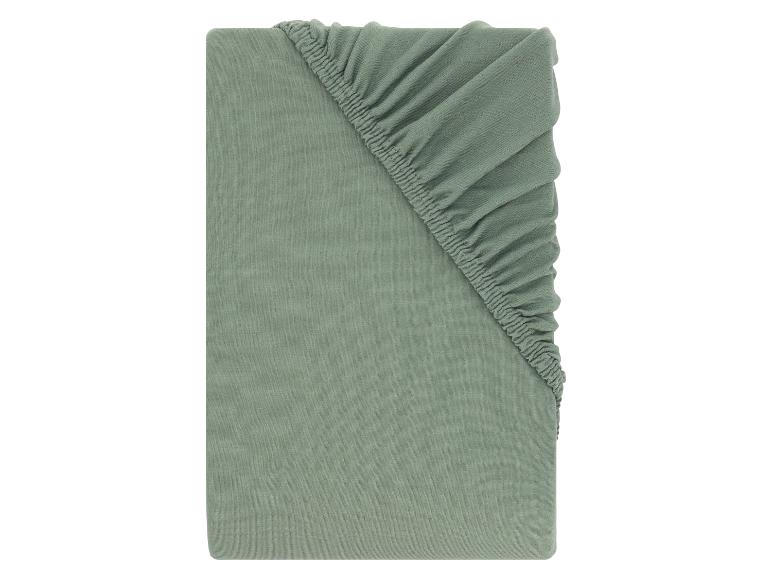 Drap-housse vert, plié, avec coin élastique visible.