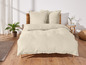 Couette beige avec taies d'oreiller assorties sur un lit en bois.