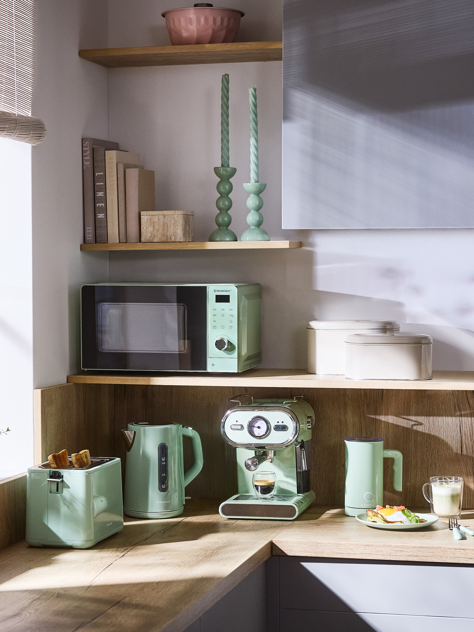 Coin cuisine avec appareils vert menthe : micro-ondes, grille-pain, bouilloire et machine à expresso.