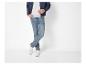 Homme en blouson aviateur bleu, t-shirt gris, jean et baskets blanches.