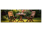 Table et chaises en bois dans un jardin fleuri.