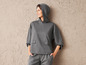 Une femme porte un sweat-shirt à capuche gris et un pantalon