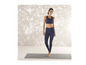 Une femme pose en soutien-gorge de sport et leggings à imprimé zèbre sur un tapis de yoga.