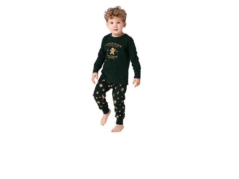 Jeune garçon en pyjama de Noël vert foncé avec des motifs de bonhommes de pain d'épices.