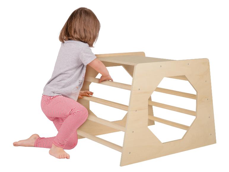 Un enfant grimpe sur une aire de jeux en bois.