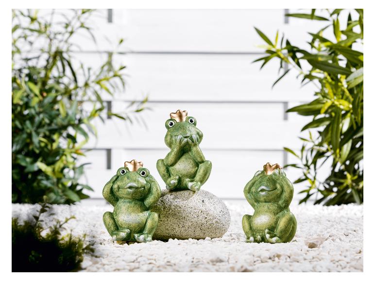 Trois grenouilles vertes avec des couronnes dorées dans un environnement de jardin.
