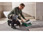 Homme coupant des carreaux avec un coupe-carreaux électrique, portant genouillères et lunettes.