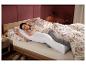 Une femme dort dans un lit avec un long oreiller.