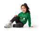 Petite fille portant un sweat-shirt vert Peanuts et des baskets grises.