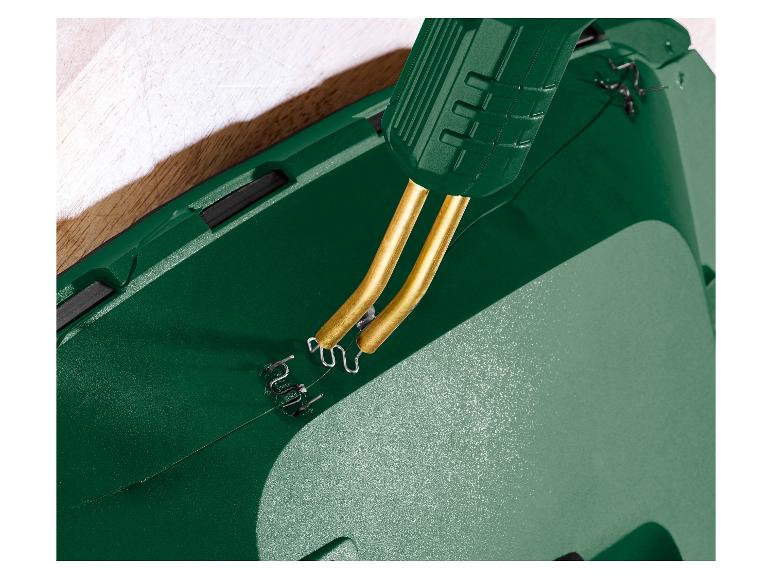 Gros plan d'un soudeur plastique vert avec des agrafes métalliques réparant une fissure.