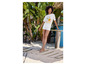 Une femme porte un t-shirt blanc à imprimé floral et un short blanc sur la plage.
