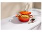 Cocotte orange avec poulet rôti et légumes sur un comptoir blanc.