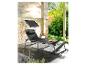 Une chaise longue noire avec un parasol sur une terrasse.