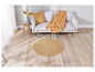 Un tapis rond en jute devant un canapé blanc avec une couverture beige.