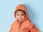Un enfant porte un imperméable orange à capuche.