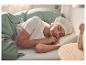 Femme dormant dans un lit en t-shirt blanc et bonnet de nuit, couverte d'une parure de lit verte.