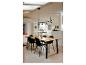 Salle à manger avec table en bois, chaises noires et suspension moderne.