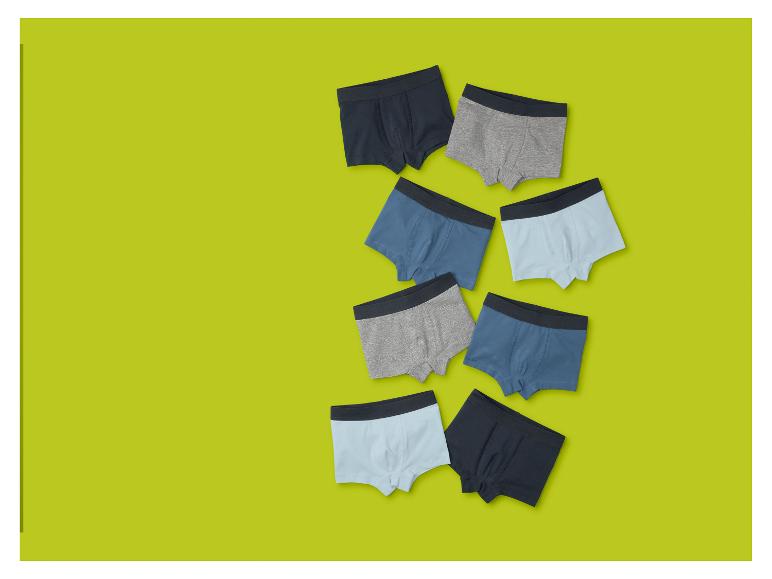 Huit boxers pour garçons dans différentes nuances de bleu et de gris sur fond vert lime.