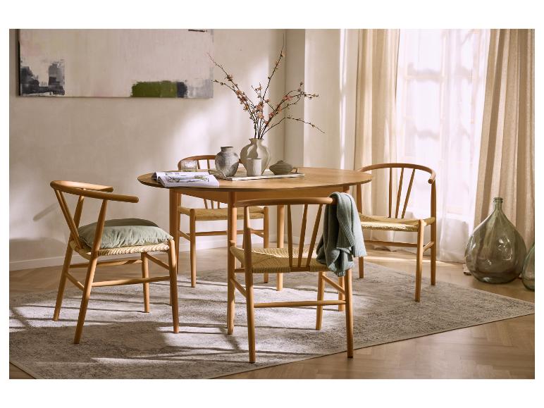 Table à manger ronde en bois avec quatre chaises, un tapis et un vase de fleurs.