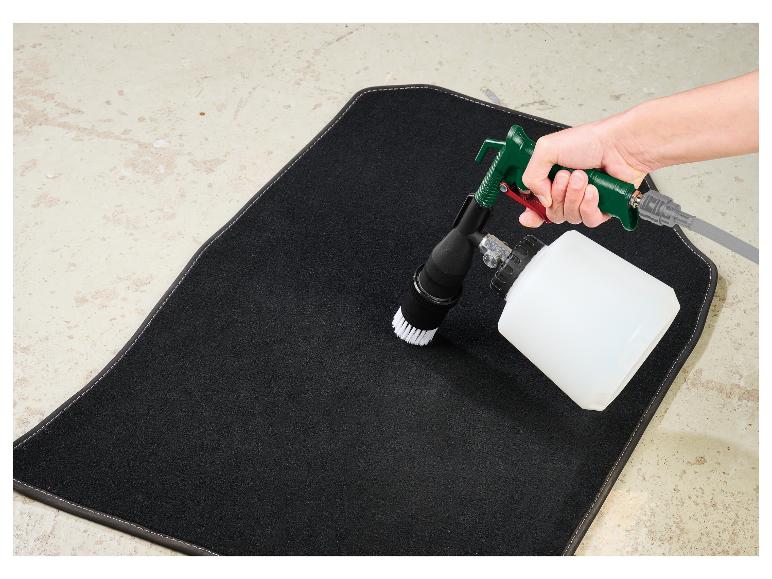 Nettoyage d'un tapis de voiture noir avec un pistolet de nettoyage à mousse