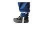 Gros plan d'une jambe d'enfant en pantalon imperméable bleu avec bande réfléchissante et chaussure grise.