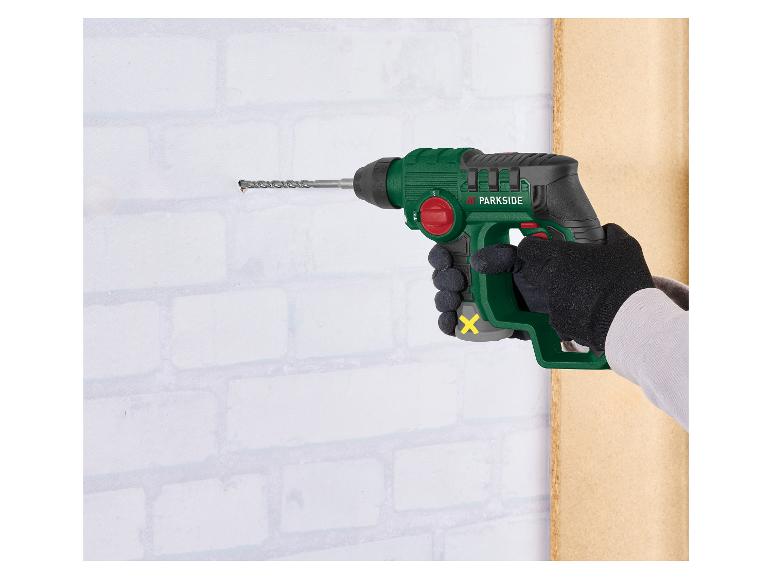 Perceuse à main perçant un trou dans un mur de briques blanches.