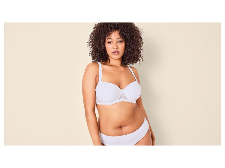 Femme aux cheveux bouclés portant un soutien-gorge et une culotte blancs.