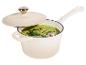 Casserole de couleur crème avec couvercle, remplie de soupe verte garnie d'herbes et de grains de poivre rose.