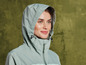Une femme porte une veste verte claire à capuche.