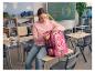 Une fille assise sur un pupitre d'école ouvre son sac à dos rose CRELANDO®.