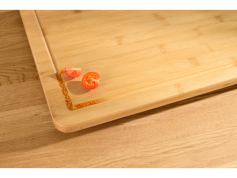 Planche à découper en bois avec des tomates cerises coupées et du jus.