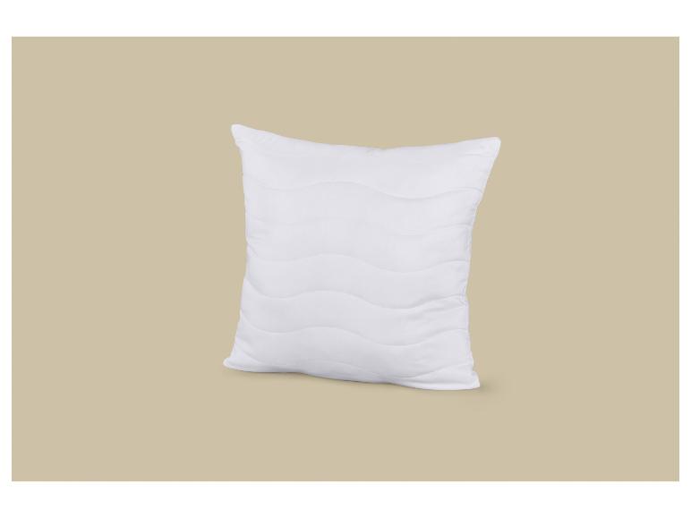 Oreiller blanc avec motif ondulé sur fond beige