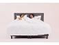 Un couple au lit avec des draps blancs et des oreillers.