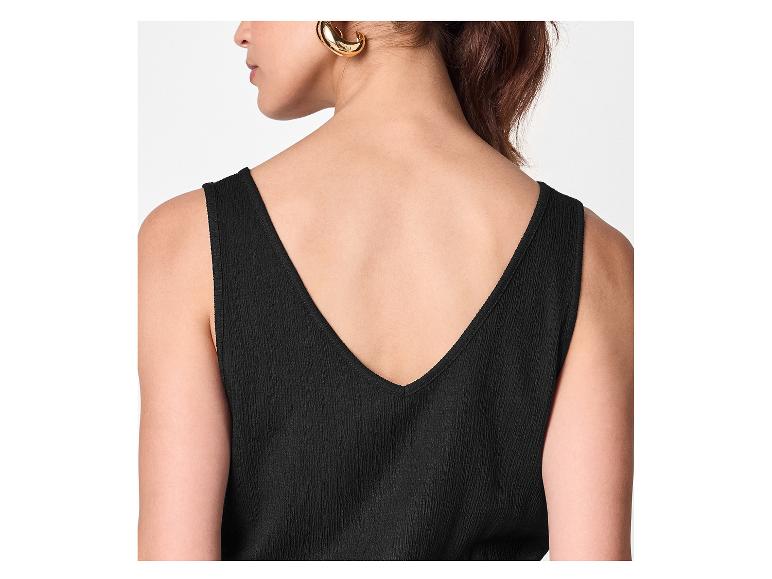 Femme en top noir avec décolleté en V dans le dos et boucles d'oreilles dorées.