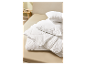 Couette et oreillers blancs en coton sur un lit.