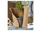 Plante en pot enveloppée dans un matériau de protection en jute, avec du bois de chauffage en arrière-plan.