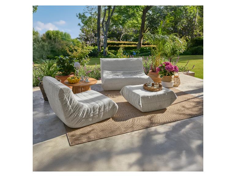 Coin salon extérieur avec sièges modulaires gris clair, une table d'appoint en bois et des plantes en pot.