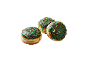 Trois beignets au glaçage chocolat, décorés de glaçage vert et de pistaches hachées.