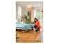 Femme passant l'aspirateur sous le lit dans la chambre avec un aspirateur balai.