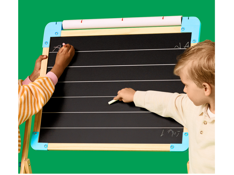 Deux enfants écrivant à la craie sur un tableau noir ligné pour apprendre à écrire.