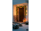 Guirlande lumineuse de Noël sur la porte d'entrée avec une luge et une lanterne dans un paysage enneigé.