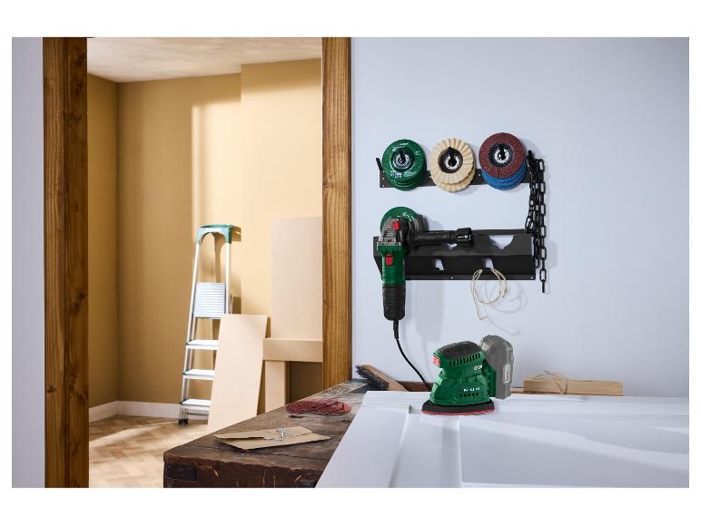 Scène d'atelier avec une meuleuse et une ponceuse sur un établi, avec des disques de ponçage au mur.