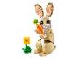 Lapin LEGO en briques de couleur sable tenant une carotte, avec une fleur jaune à côté.
