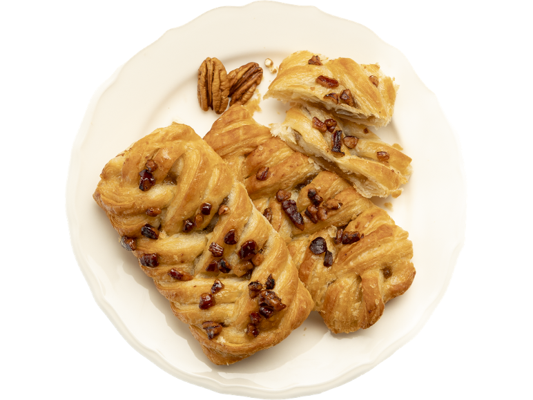 Tresses et pâtisseries aux noix de pécan sur une assiette blanche, garnies de noix de pécan entières.