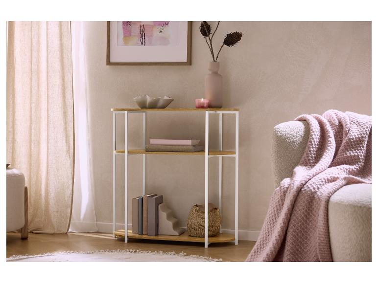 Étagère en bois avec cadre blanc, livres, vase et bougie dans un salon.